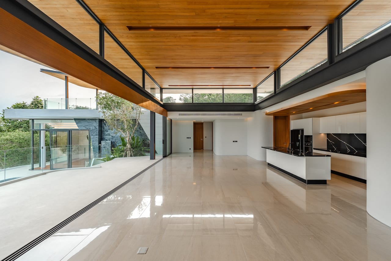 Open-concept living space with a white glossy floor, wood ceiling, black marble backsplash, and expansive glass walls.
