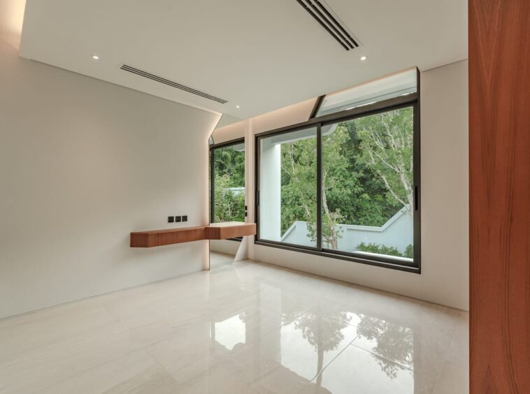 Bright minimal room with a glossy white floor, large windows, and a floating wooden desk along the wall.