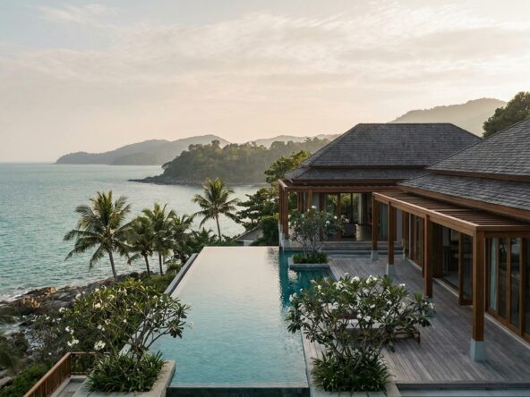 Luxurious seaside villa with an infinity pool, wooden deck, and palm-fringed coastline view at sunset/enhanced by calm sea.